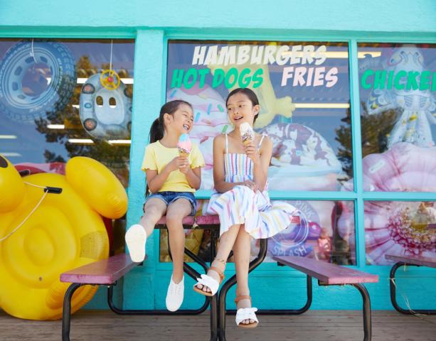 Two young girls sit outside a retro diner enjoying ice cream cones in Sylvan Lake.