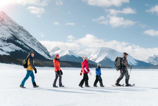 An ice fishing guide leads a young family while they trek across the frozen lake looking for an ice fishing spot near Canmore in Kananaskis Country