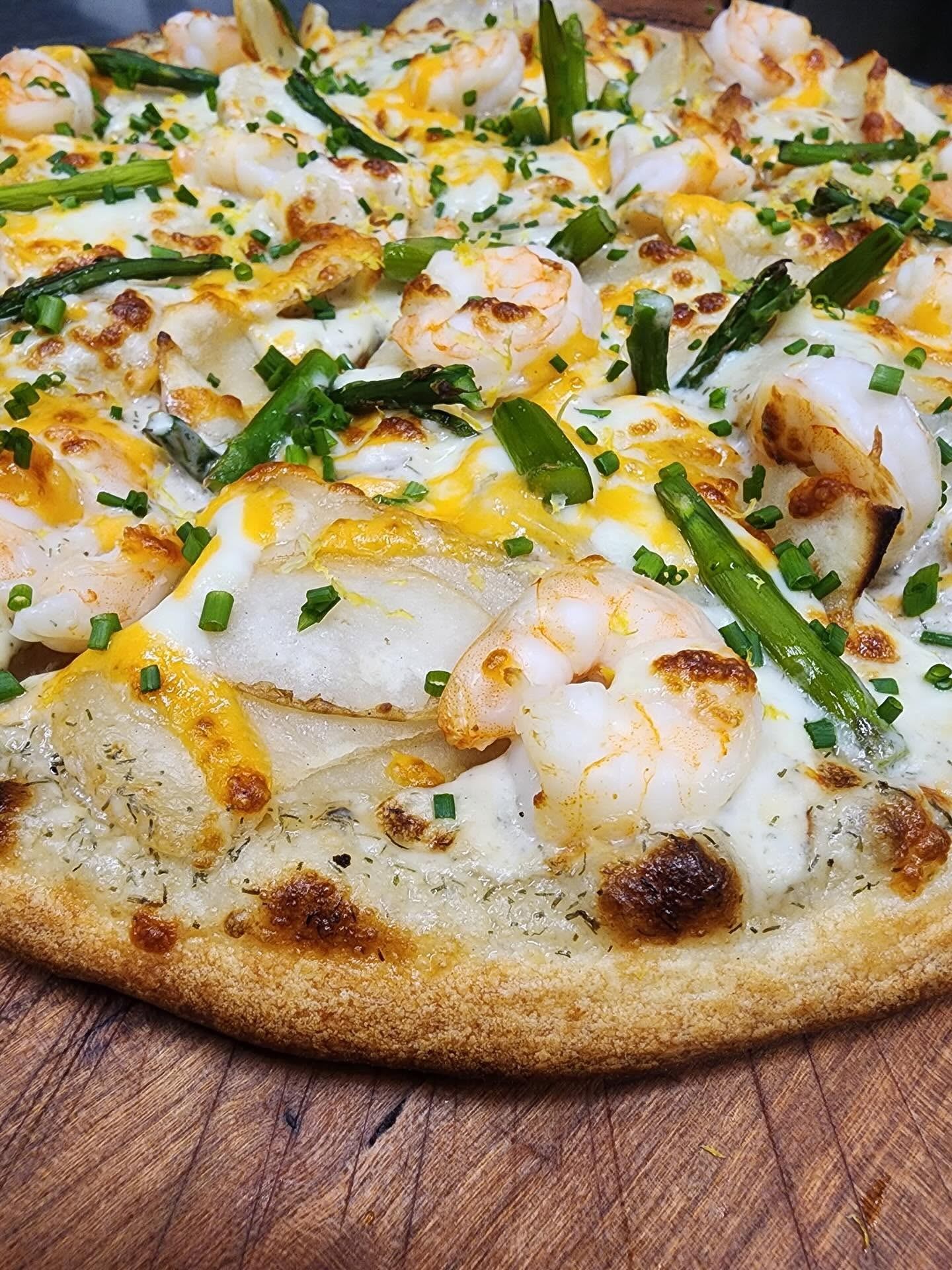 Piston Broke Brewing features a pizza topped with shrimp, cheese, and fresh green onions.