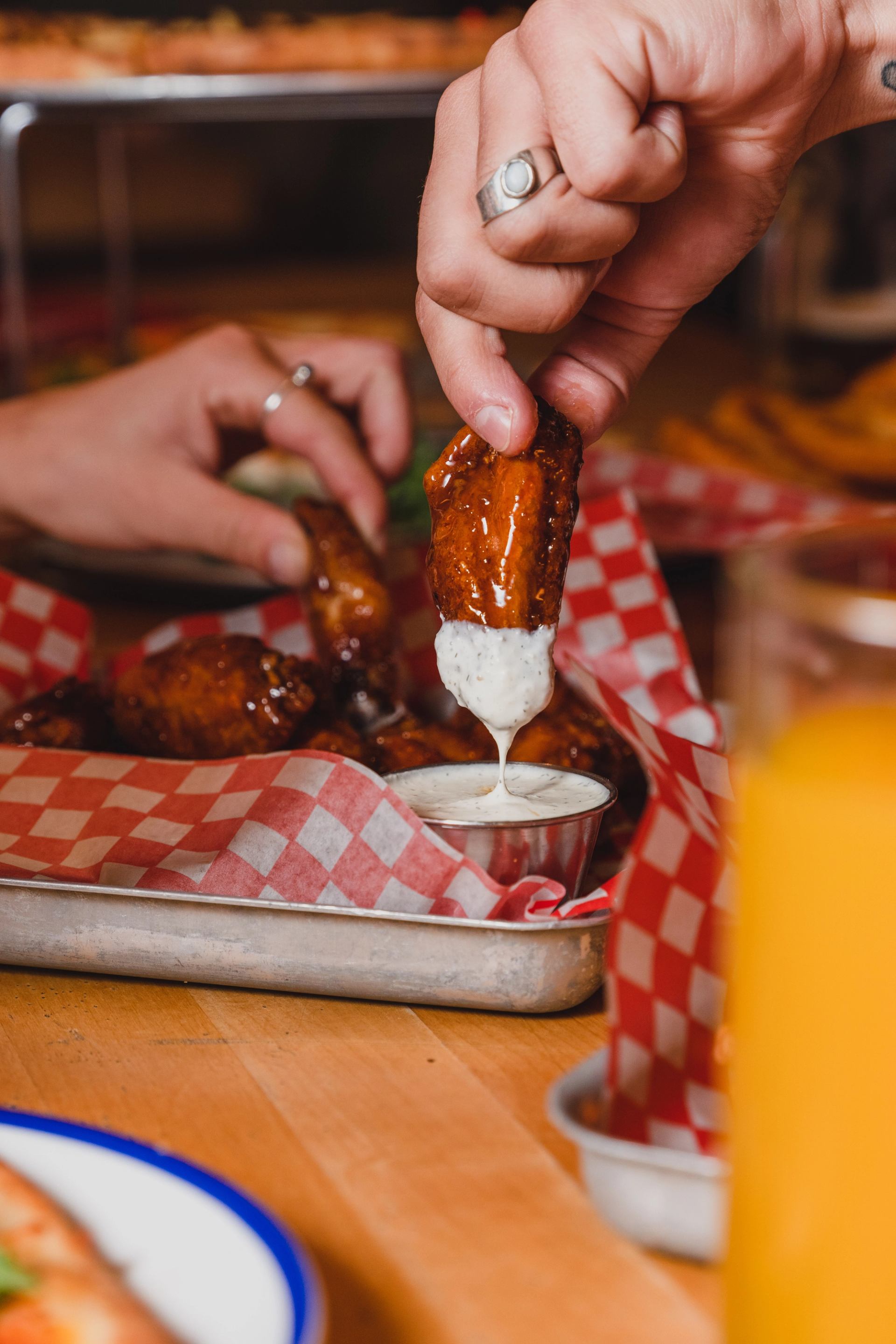 A saucy chicken wing is dipped into ranch dressing. 
