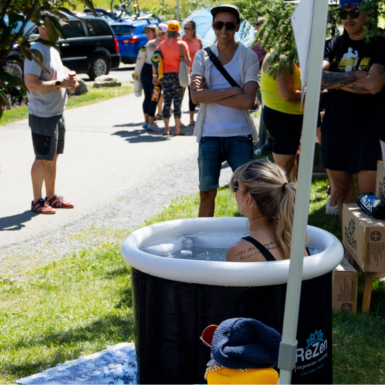 Participant sitting in an ice bath while others watch during the Rise run, yoga, mediate event.