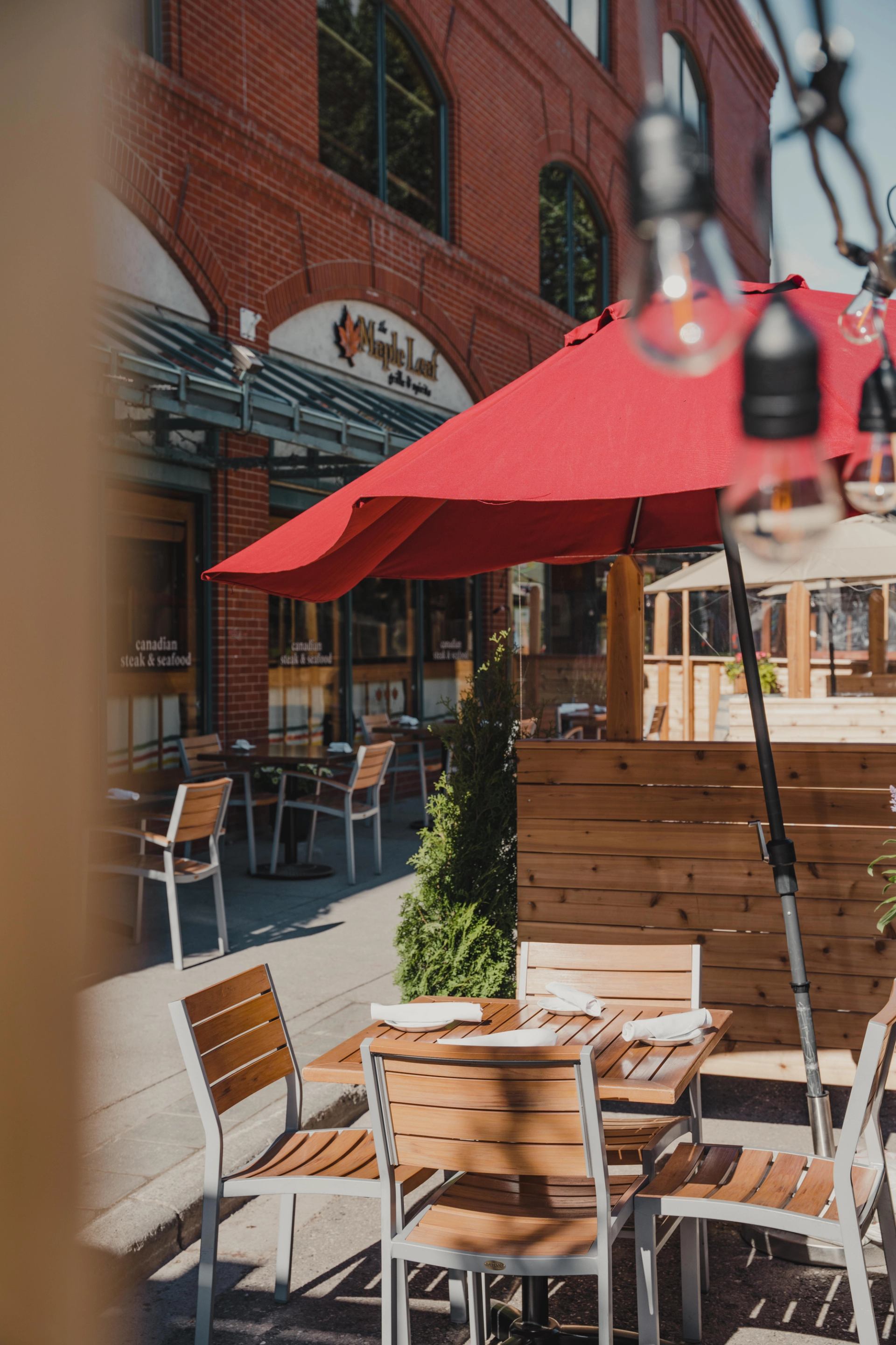 A patio umbrella shades a table on a street patio outside the front door. 