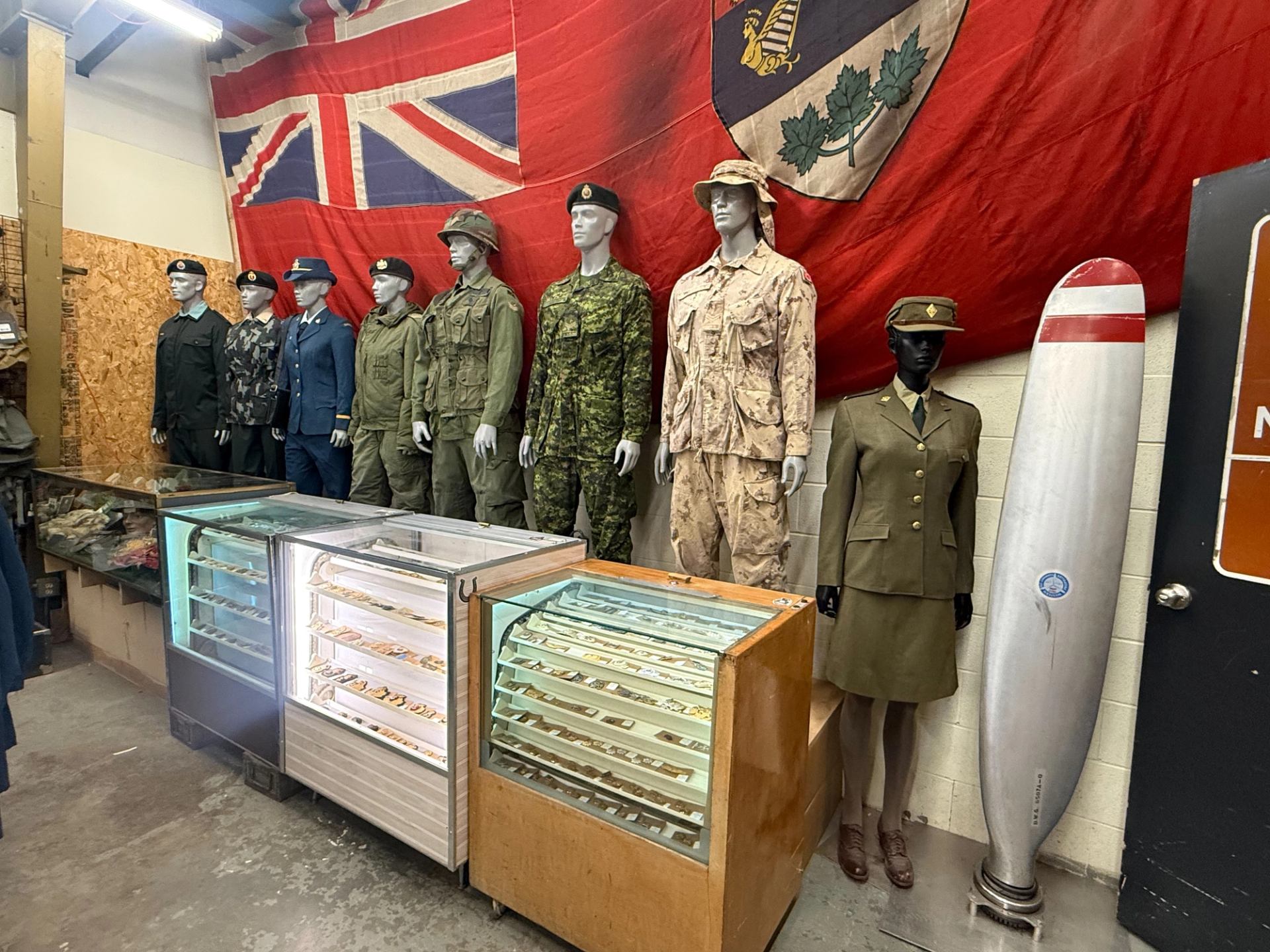 Crown Surplus Store features mannequins in various military uniforms lined beneath large flags and display cases.