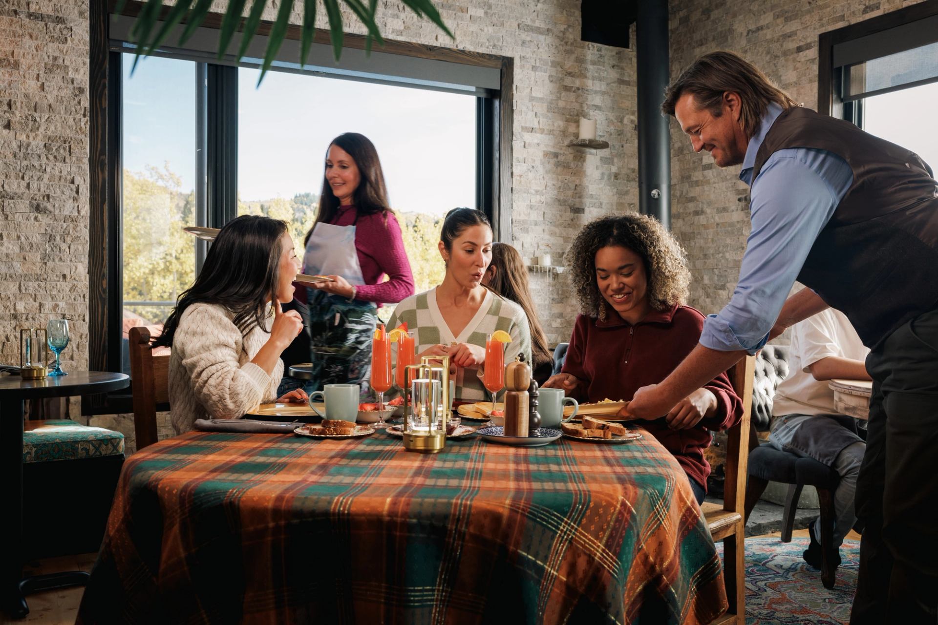 Guests sharing a meal at a sunlit table at River Retreat Kananaskis.