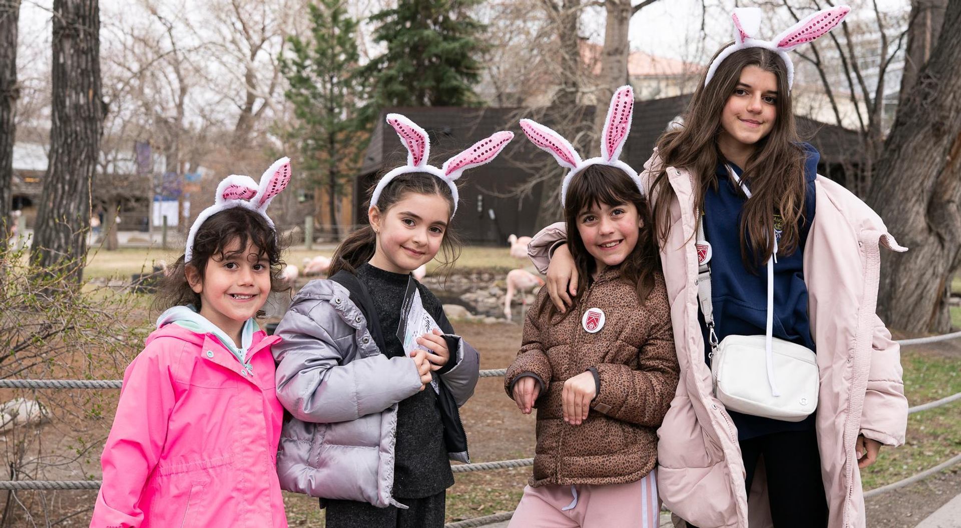 Four children wearing bunny ear headbands posing together outdoors