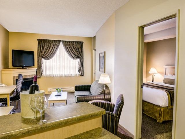Clearwater Suite Hotel room with living area, dining table, and bedroom.