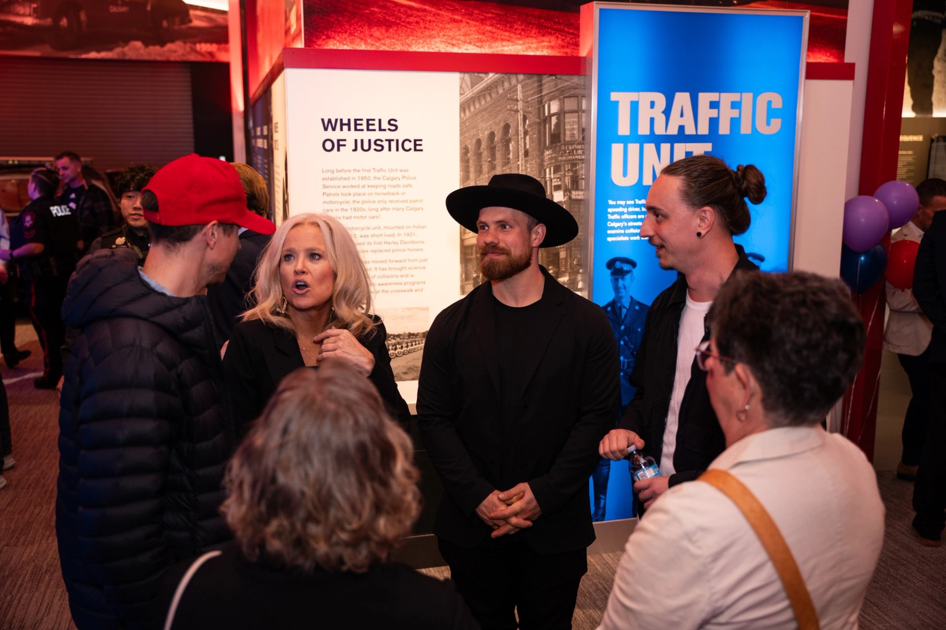 Museum visitors converse beside Wheels of Justice and Traffic Unit displays.