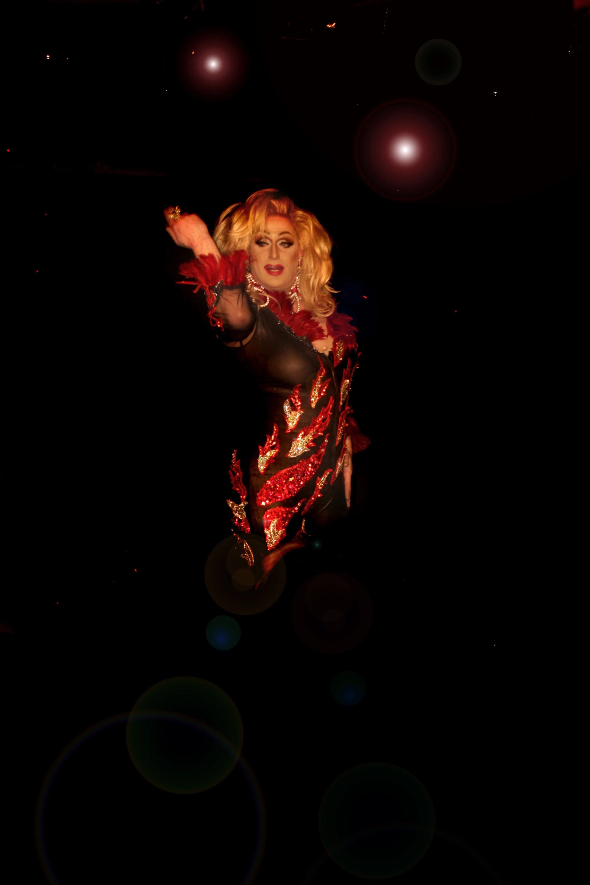 Performer in a glittering outfit striking a pose under bright stage lights.