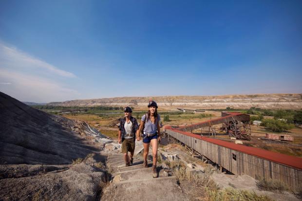 Couple walking at Atlas Coal Mine with a view of the Canadian Badlands in the background.