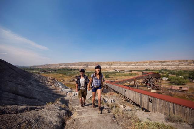 Couple walking at Atlas Coal Mine with a view of the Canadian Badlands in the background.