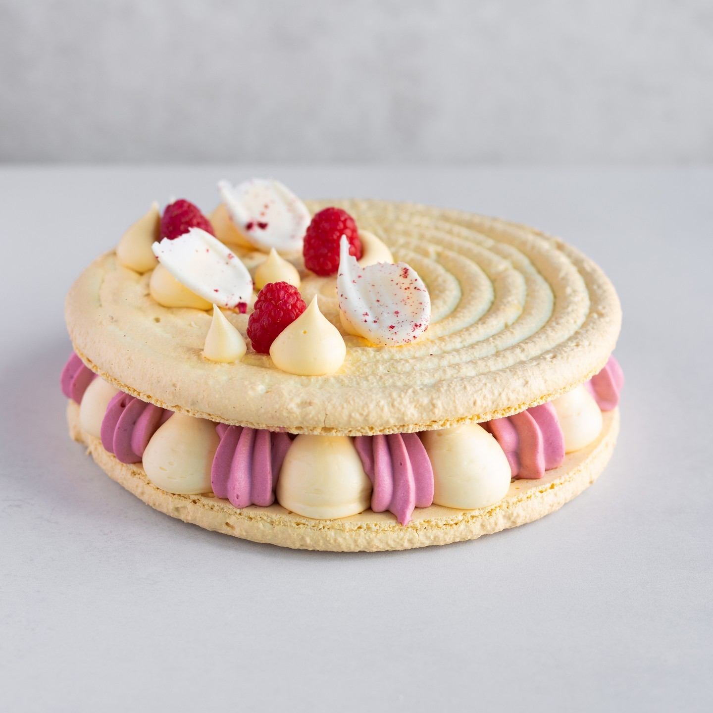 Pastry with white and purple frosting, berries, and piped cream on a bakery cake.