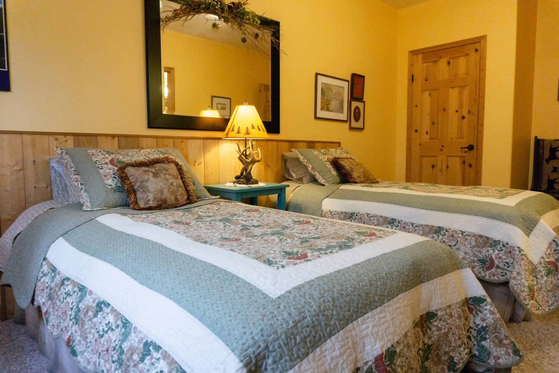Twin beds with floral quilts in a cozy yellow room.