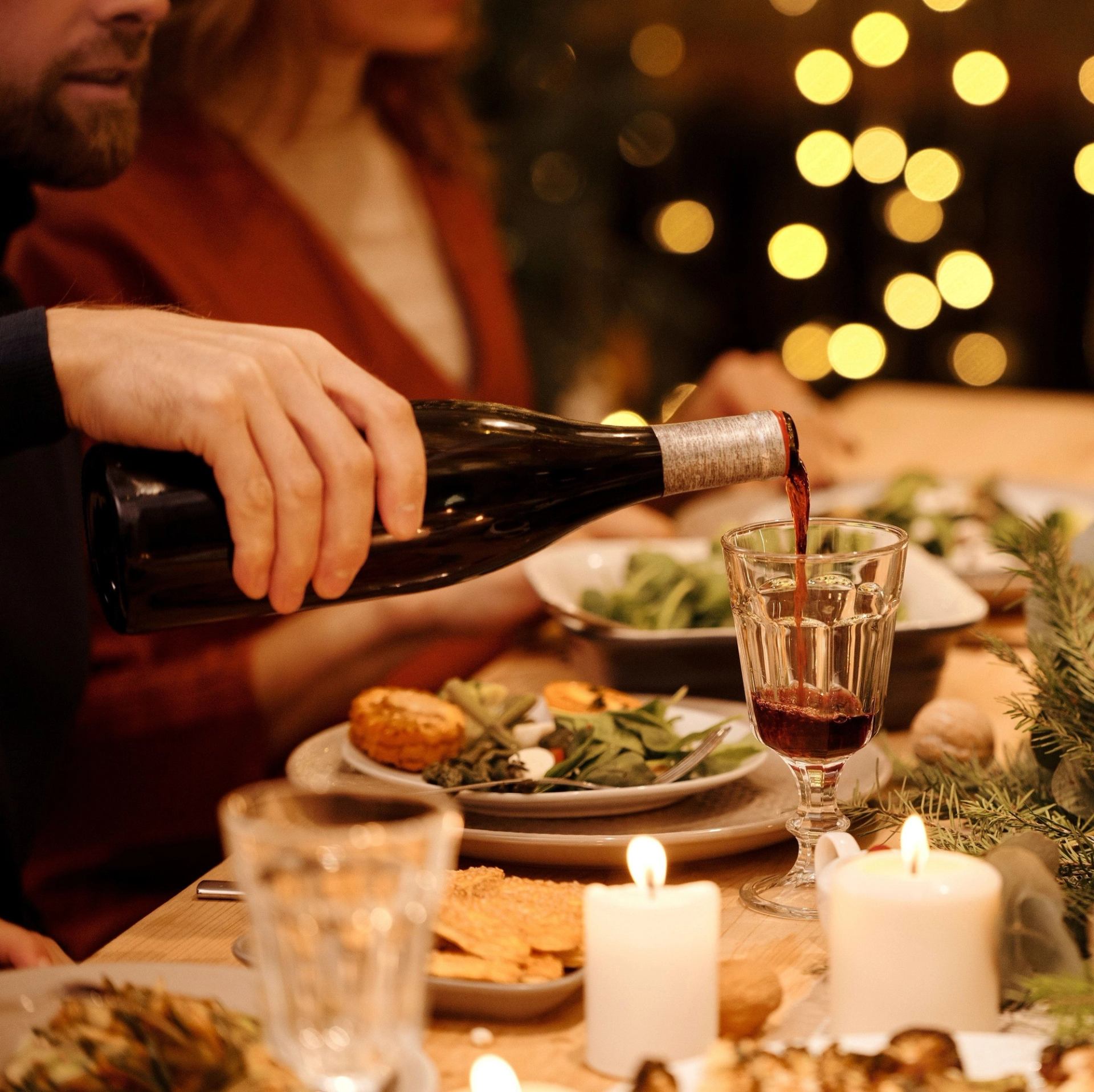 Wine being served at cozy, decorated dinner setting.