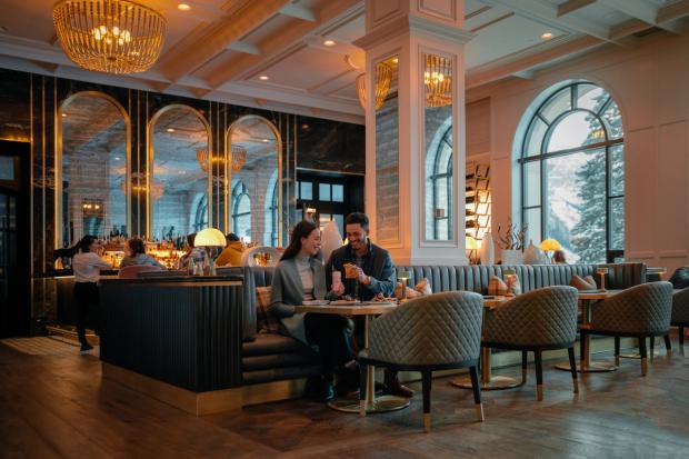 Couple enjoying drinks and food at the Fairview Lounge at the Fairmont Château Lake Louise.