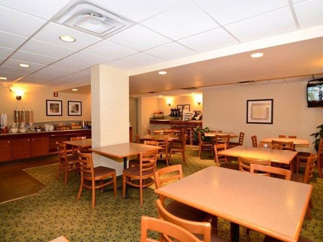 Hotel dining area with wooden tables, chairs, and breakfast buffet.
