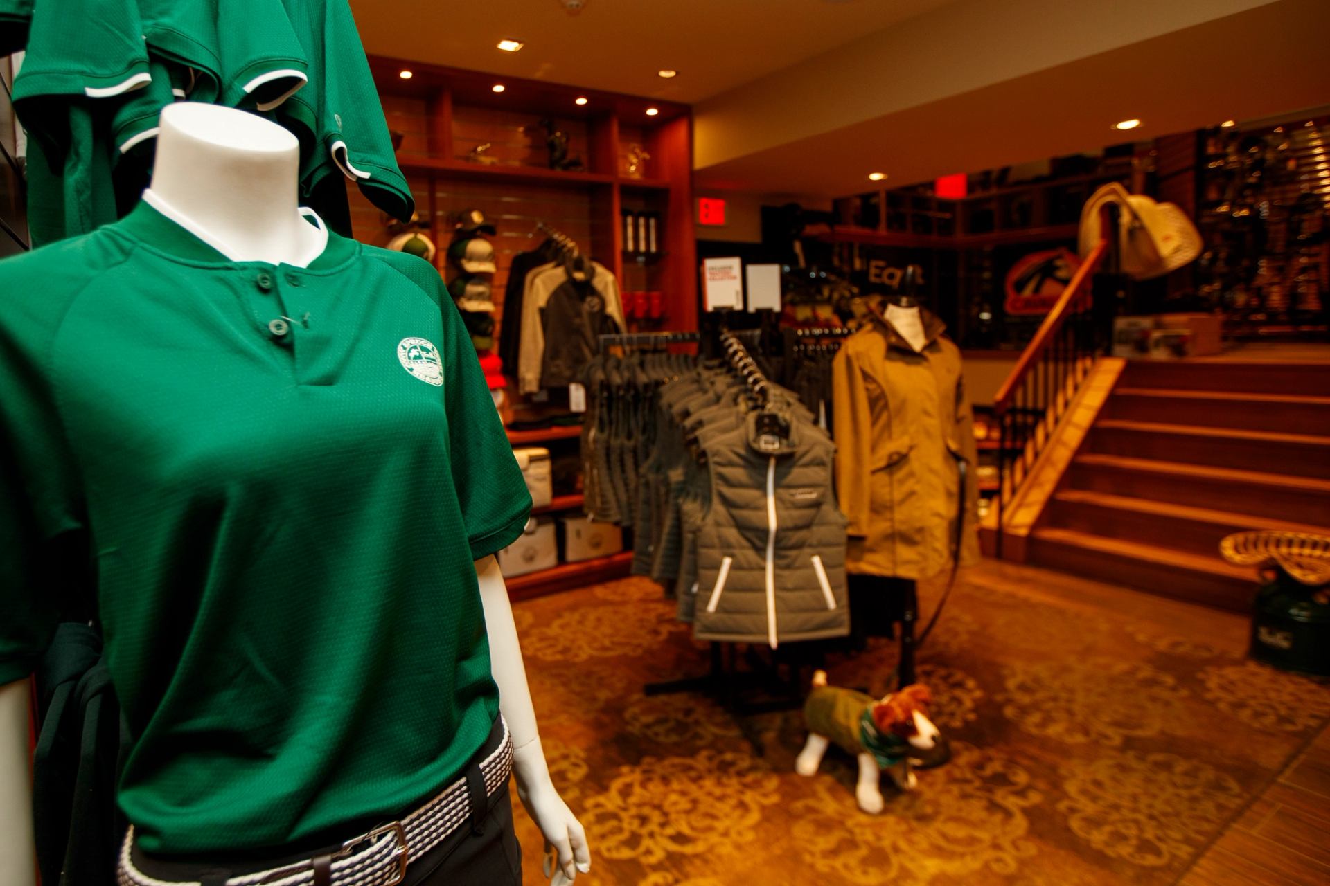 Retail shop at Spruce Meadows displaying branded apparel, jackets on racks, mannequins, and warm interior lighting.