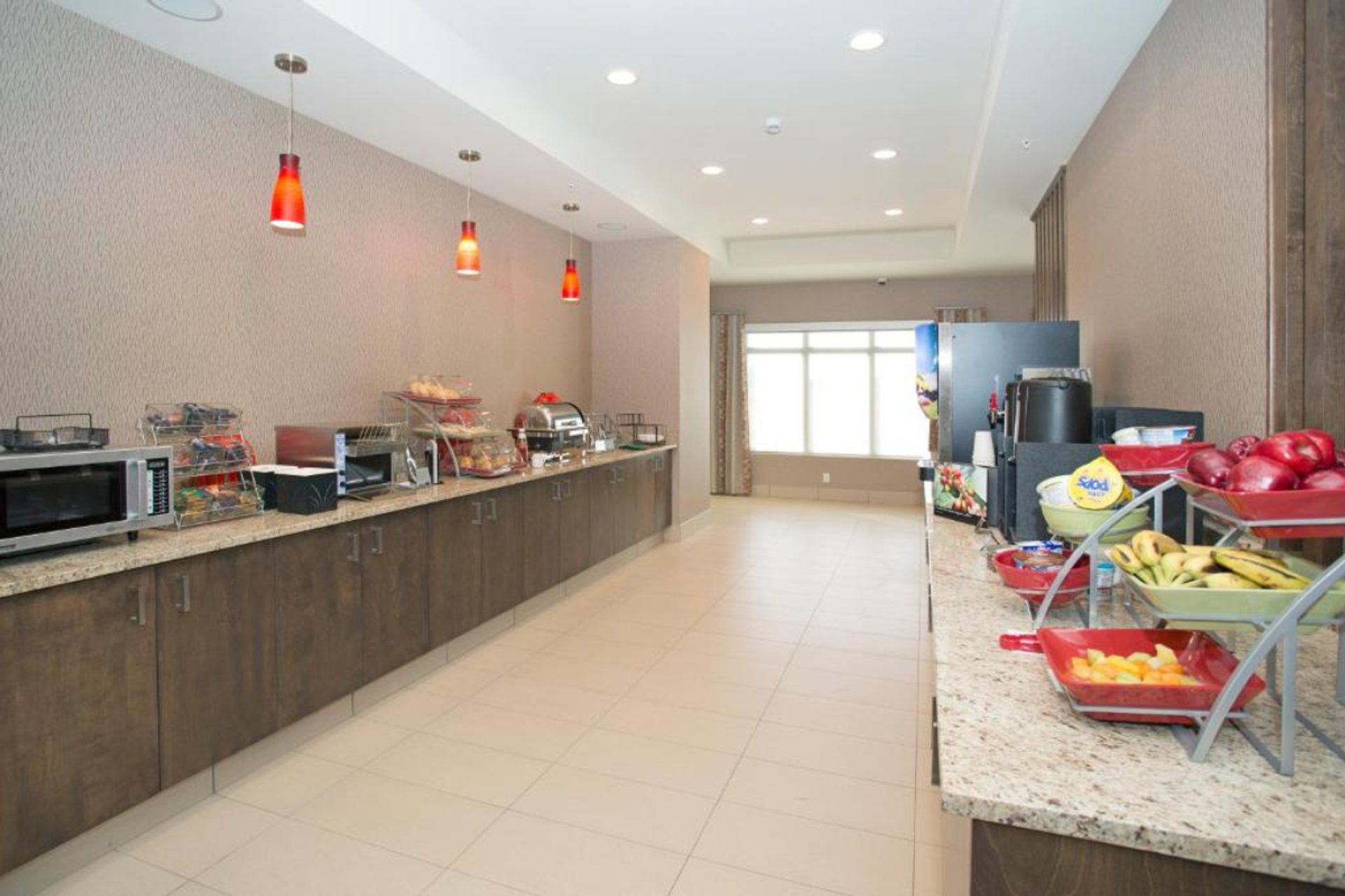 Complimentary breakfast area with counters, fruit, beverages, and food stations.