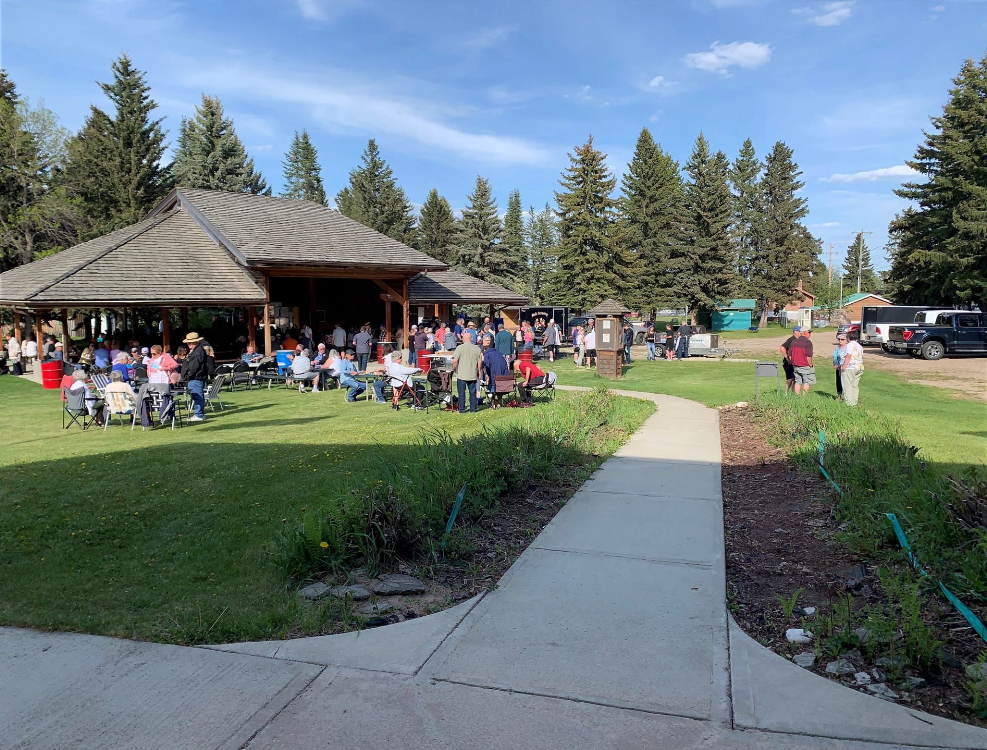 People gather near a pavilion in a grassy park