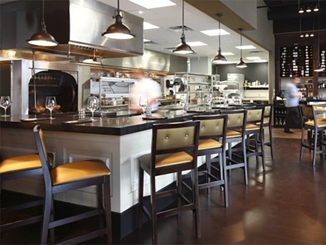 Upscale steakhouse bar with open kitchen and warm lighting.