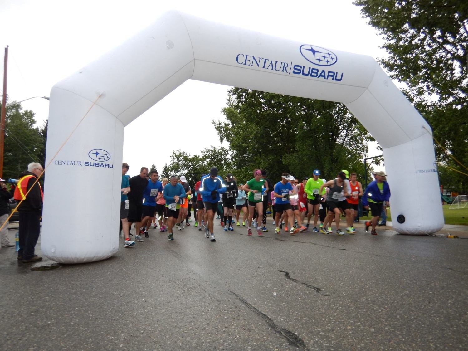 Runners line up under a Centaur Subaru inflatable arch at a relay race.