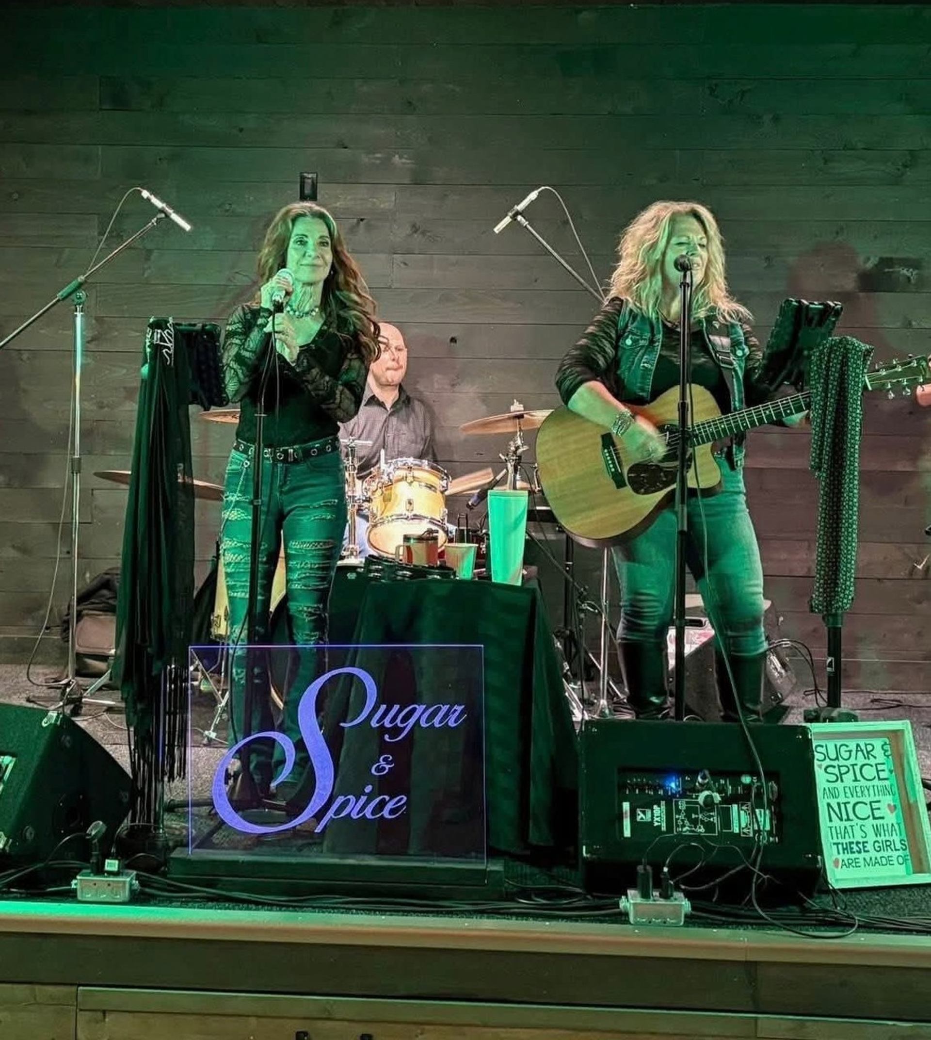 Sugar & Spice musicians sing and play guitar and drums onstage.