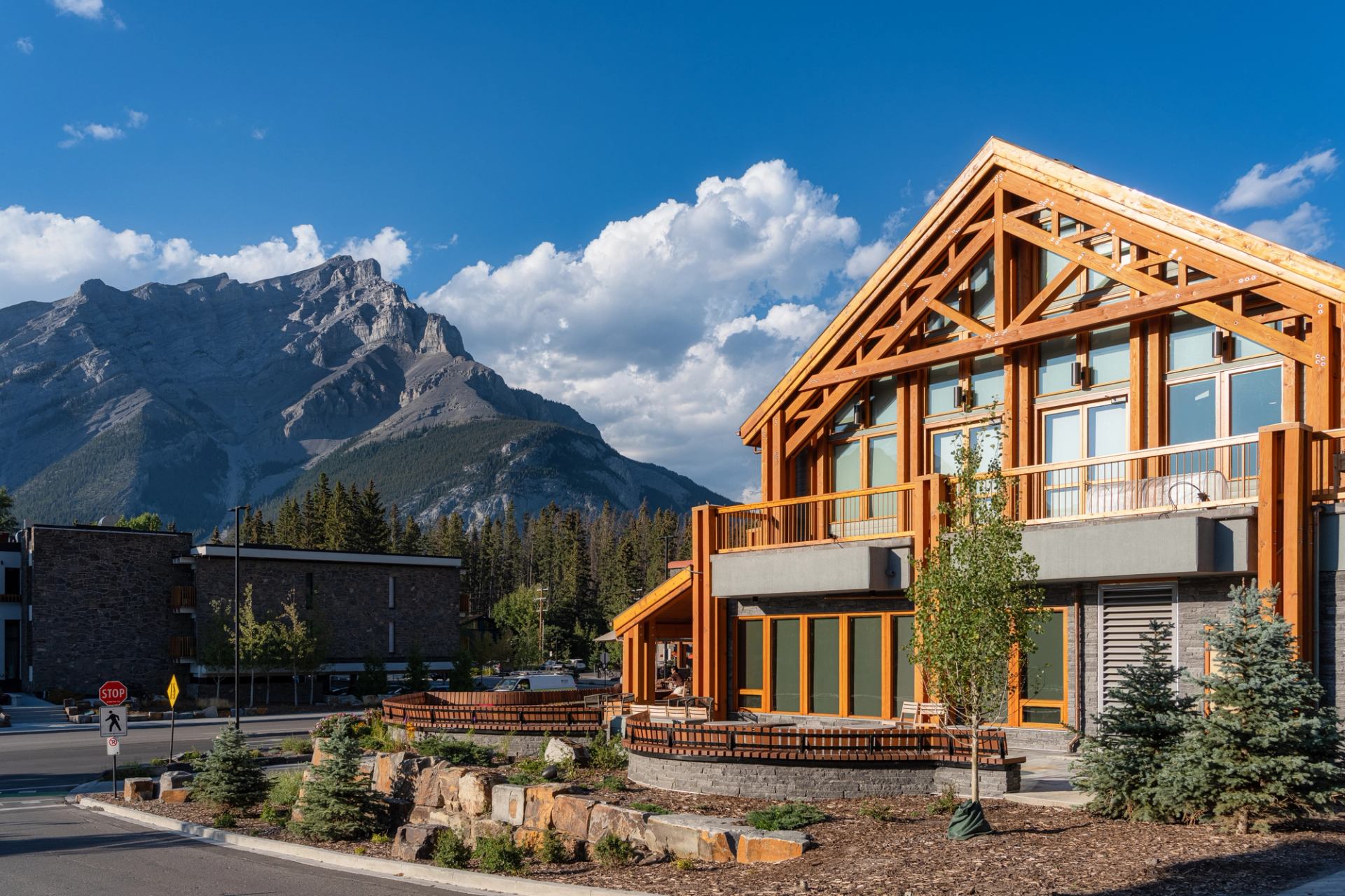 Hotel on the right with large windows and balcony. Cascade Mountain to the left with blue cloudy sky