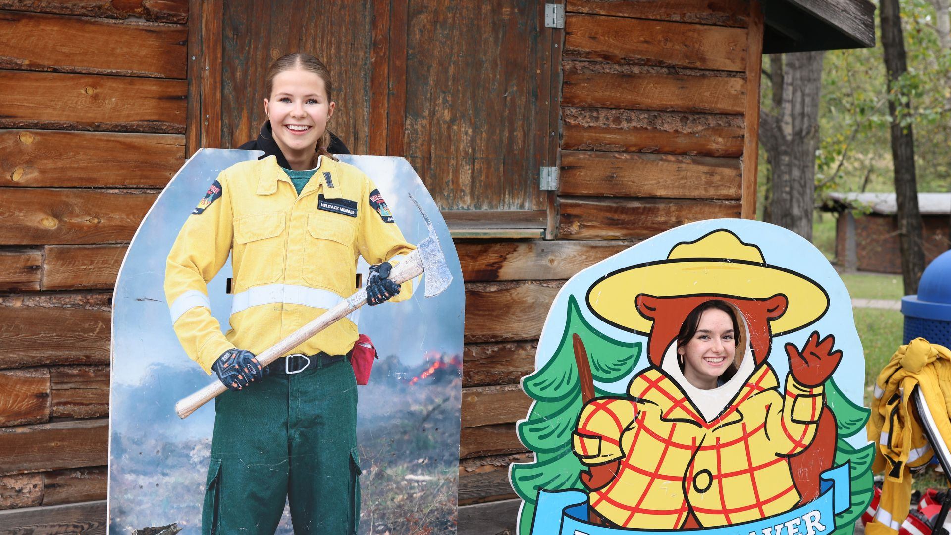 Two people pose with firefighter and Beaver cutouts at Alberta Biodiversity Festival.