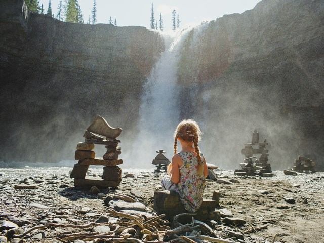 A child sitting on the ground watching the falls
