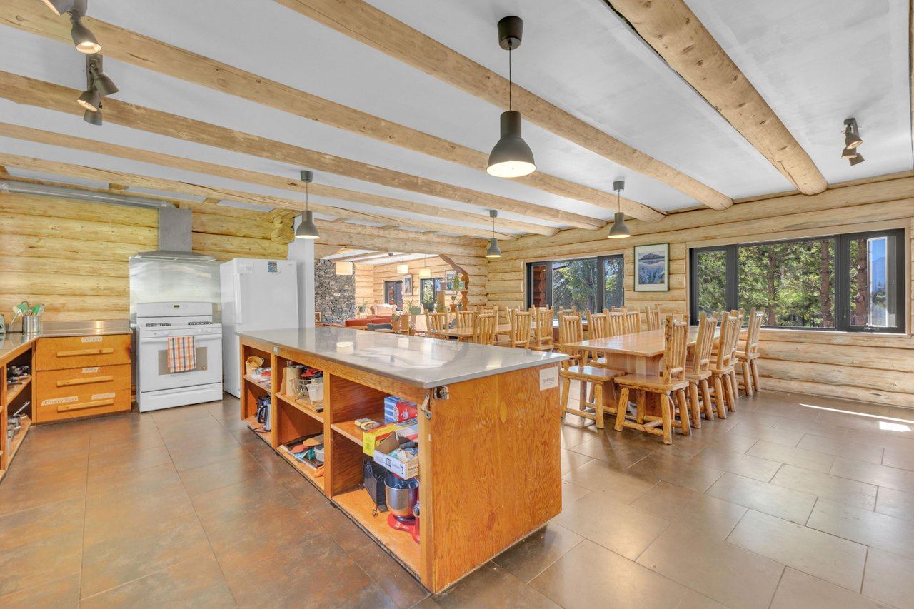 Spacious kitchen with wooden beams, a large island, and a dining area in a rustic lodge.