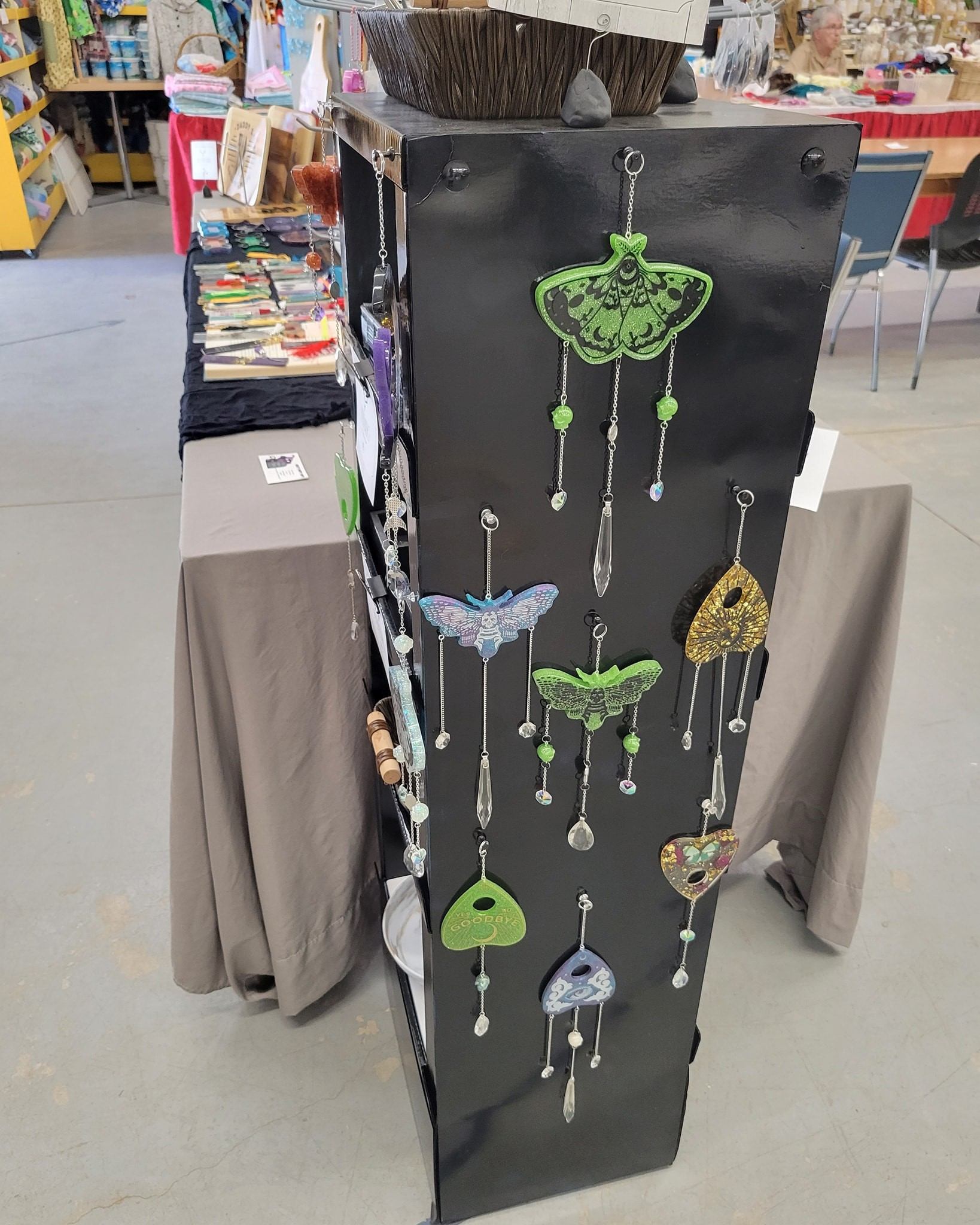 Display of colorful hanging ornaments shaped like moths and hearts on a black stand.