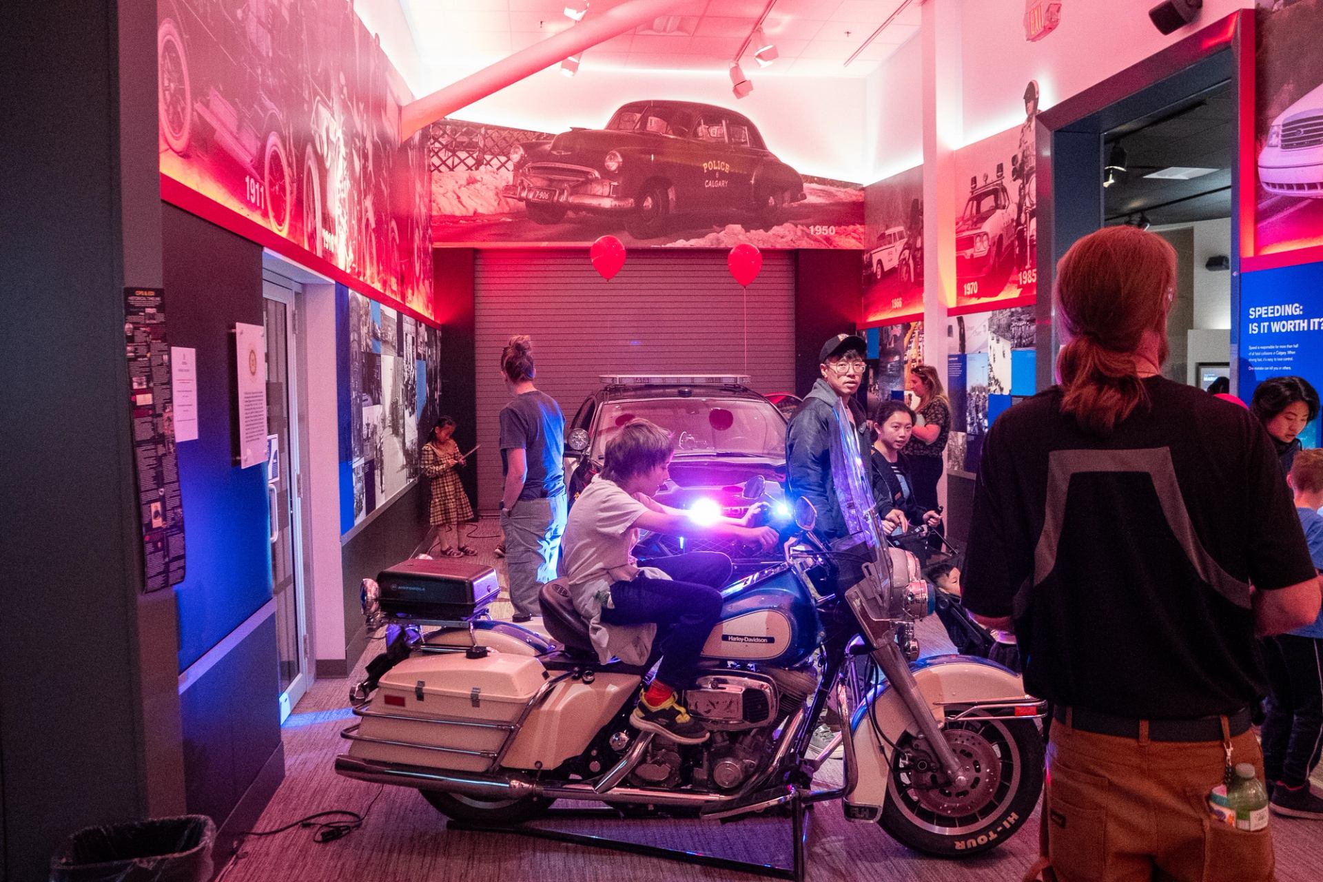 Children explore a vintage police motorcycle and car display inside a brightly lit museum.