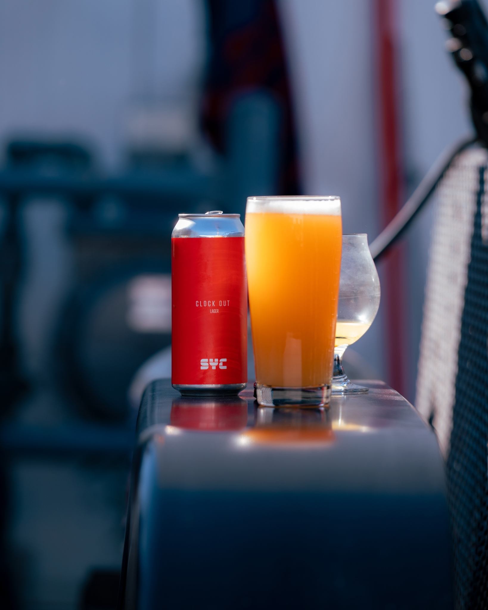S.Y.C beer can beside a full glass of beer on a ledge.