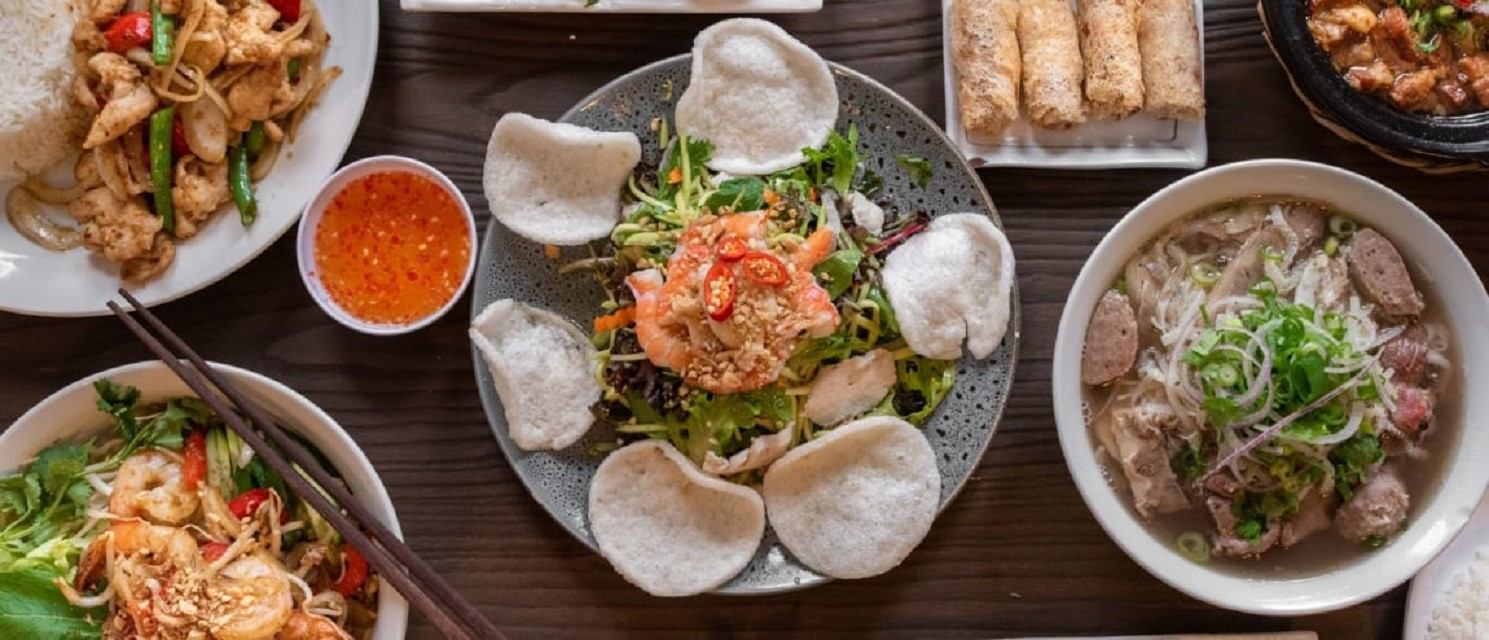 Table with pho, salad, spring rolls, and dipping sauce arranged beautifully