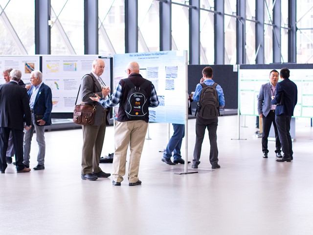 Group of professionals at a conference, discussing around exhibition posters.