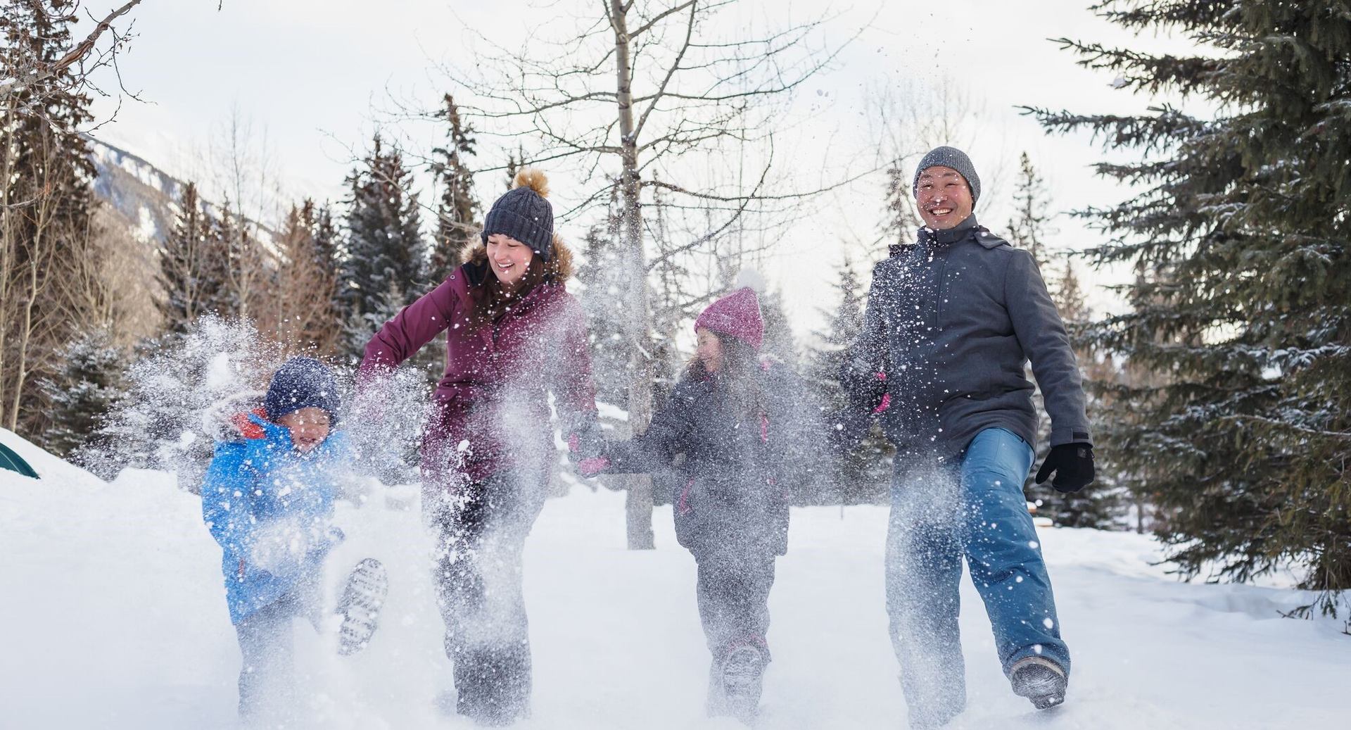Group playing in snow at outdoor winter event with trees and clear sky in background.