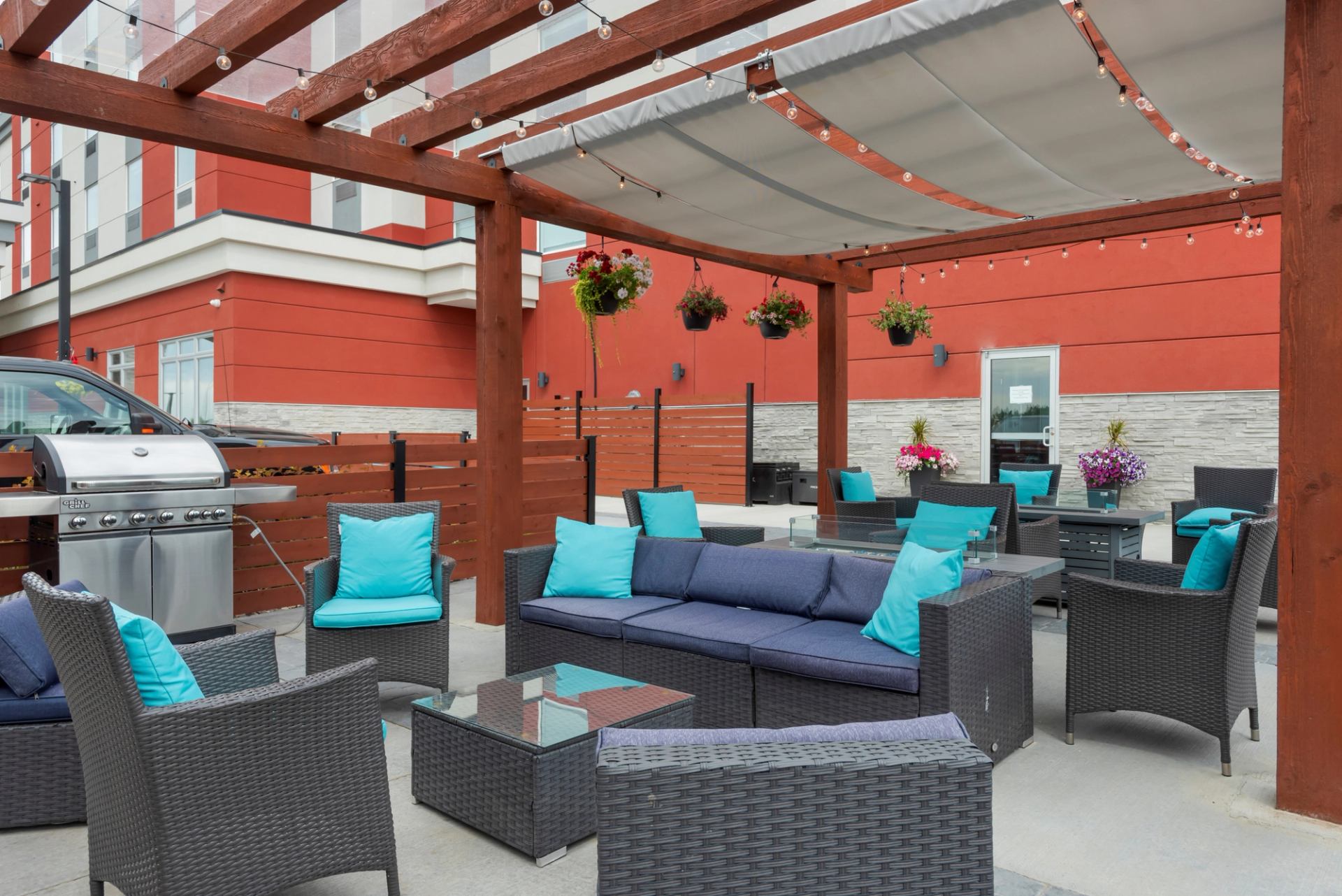 Outdoor lounge with turquoise cushions under pergola.