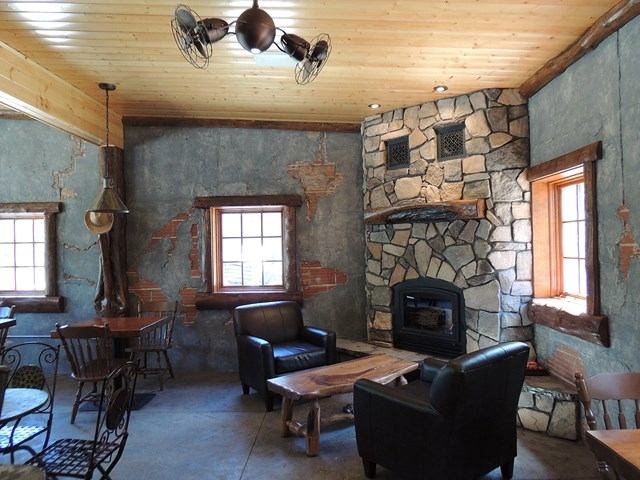 Rustic café interior with stone fireplace, leather chairs, and wooden tables.