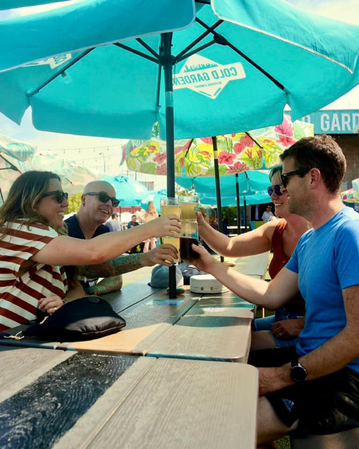 A group of four people sat on the patio with their drinks raised to cheers.