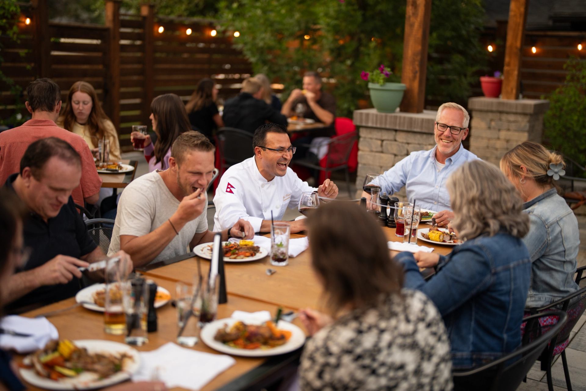 Long-table guests laughing and eating together at Cattleman's Chophouse.