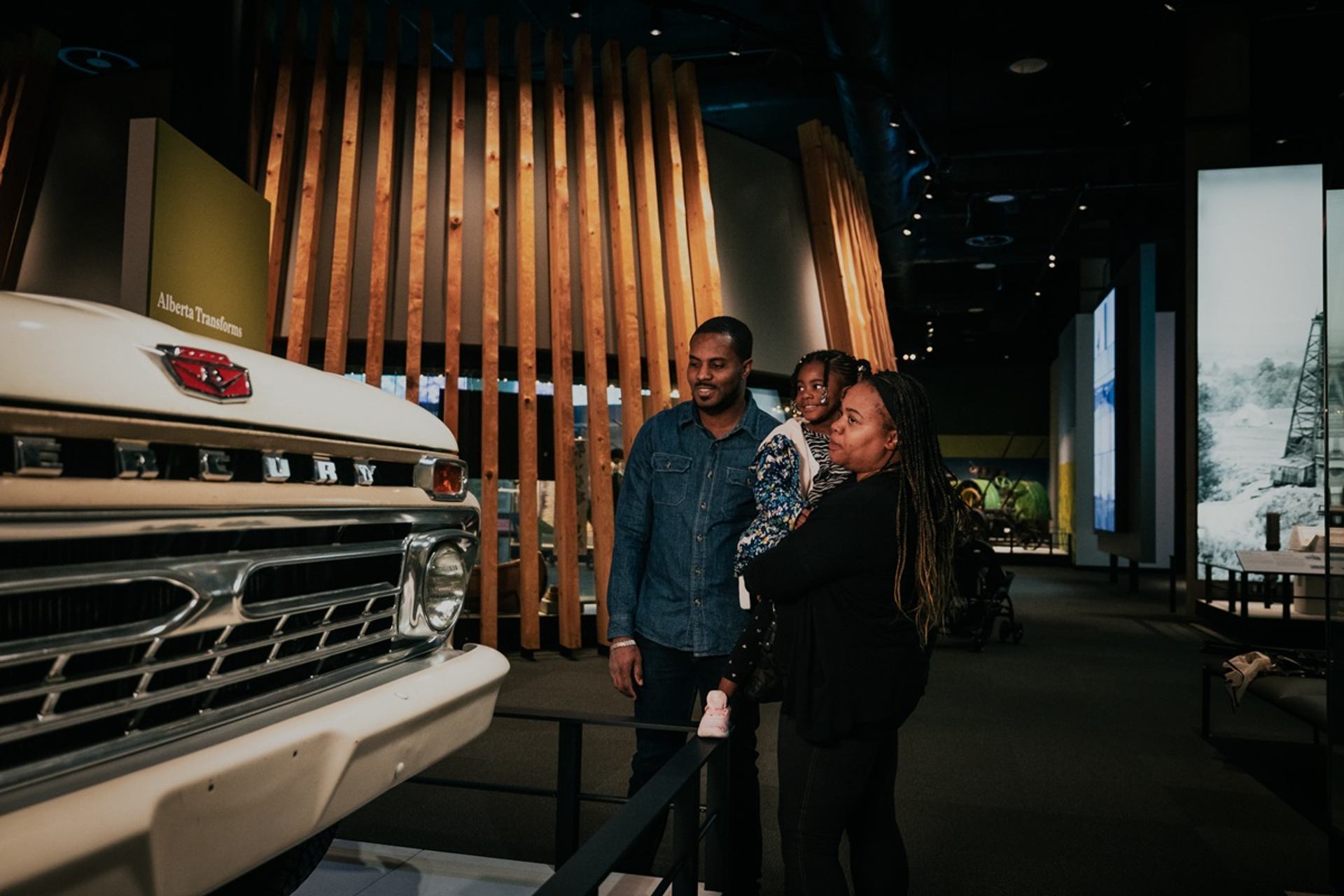 Museum visitors examine a vintage Mercury truck beside an Alberta Transforms display.