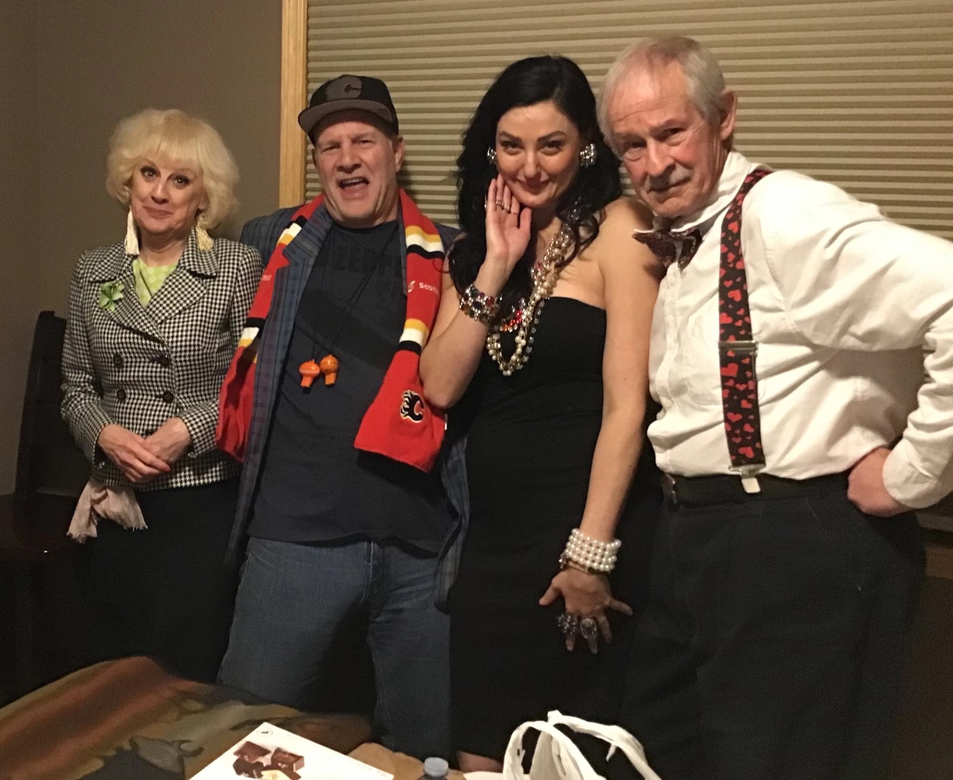 Four people in distinctive outfits pose together indoors.