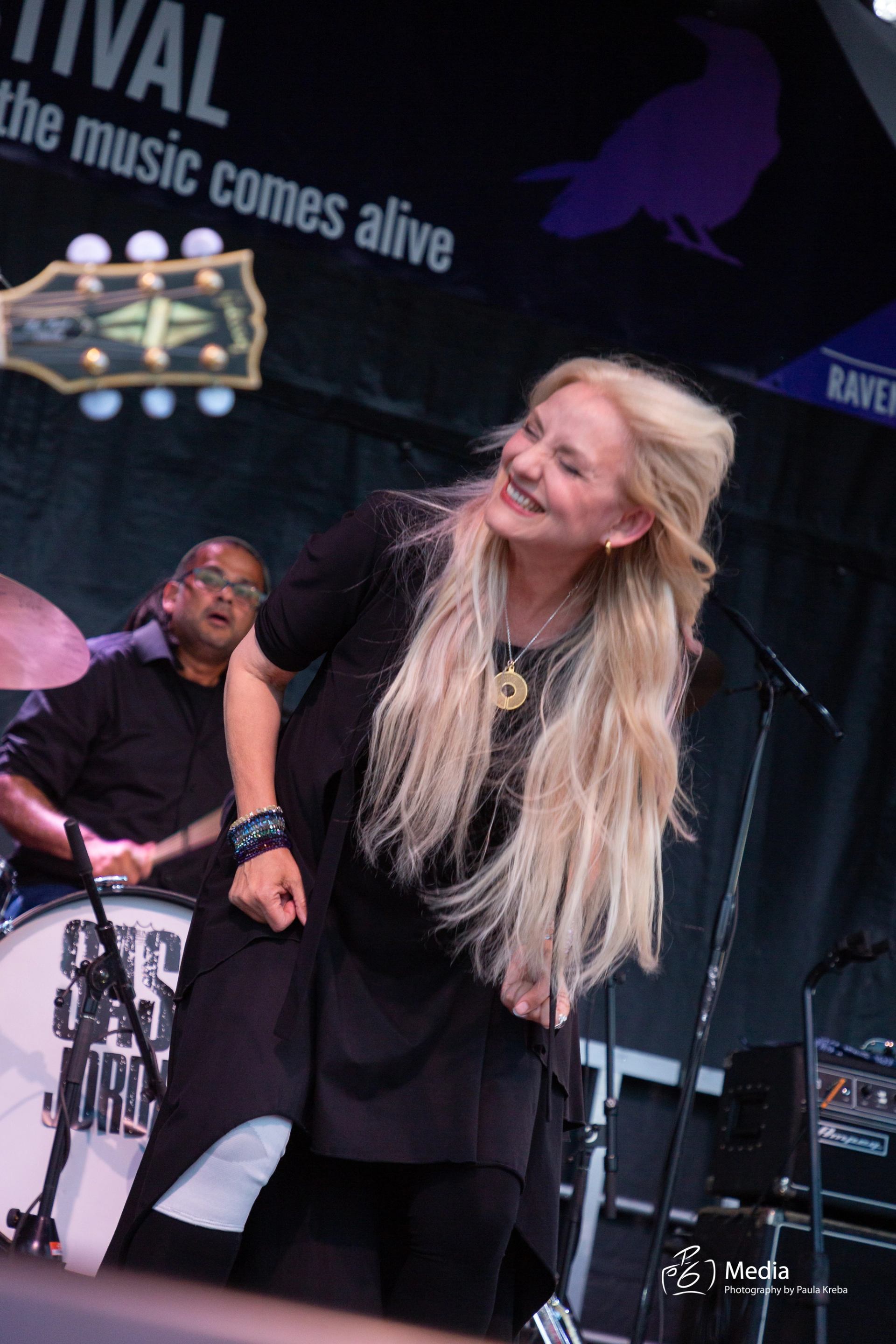 Performer with long blonde hair dancing on stage at RavenWood Music Festival.