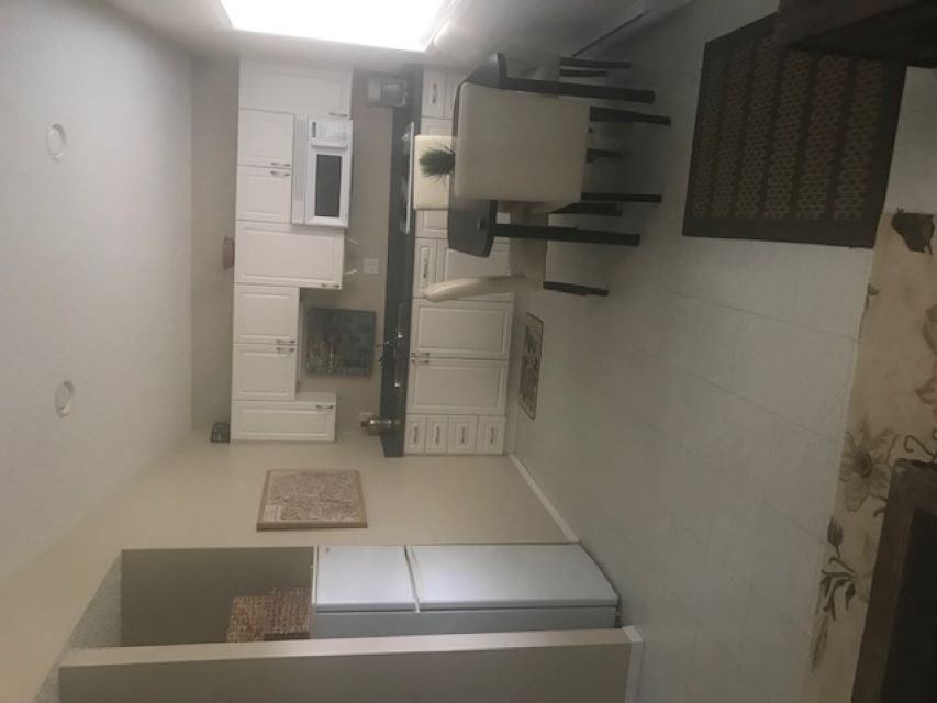 Cabin interior with a bed, kitchenette cabinets, microwave, and tiled walls.