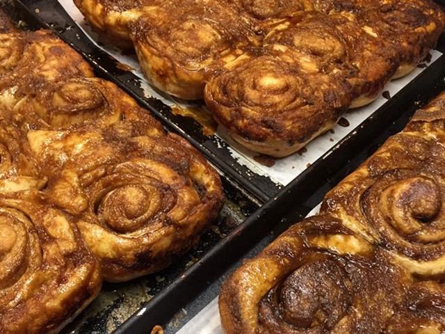 Cinnamon rolls in a baking tray, close-up showing golden brown swirls.