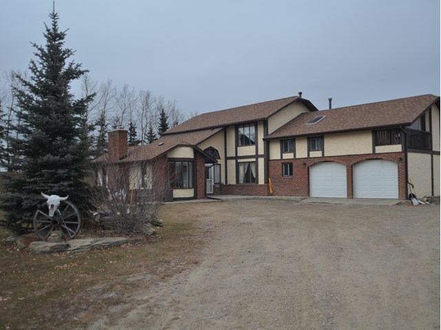 Exterior of the house with gravel driveway and tree in front.