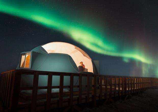 Couple looking up at Northern Lights from the Sky Watching Dome at Metis Crossing.