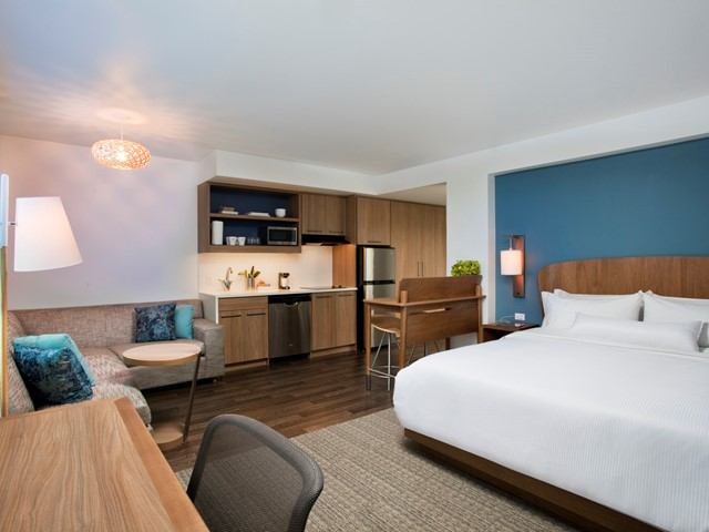 Modern hotel room with bed, sofa, desk, and kitchenette at Element Edmonton West.