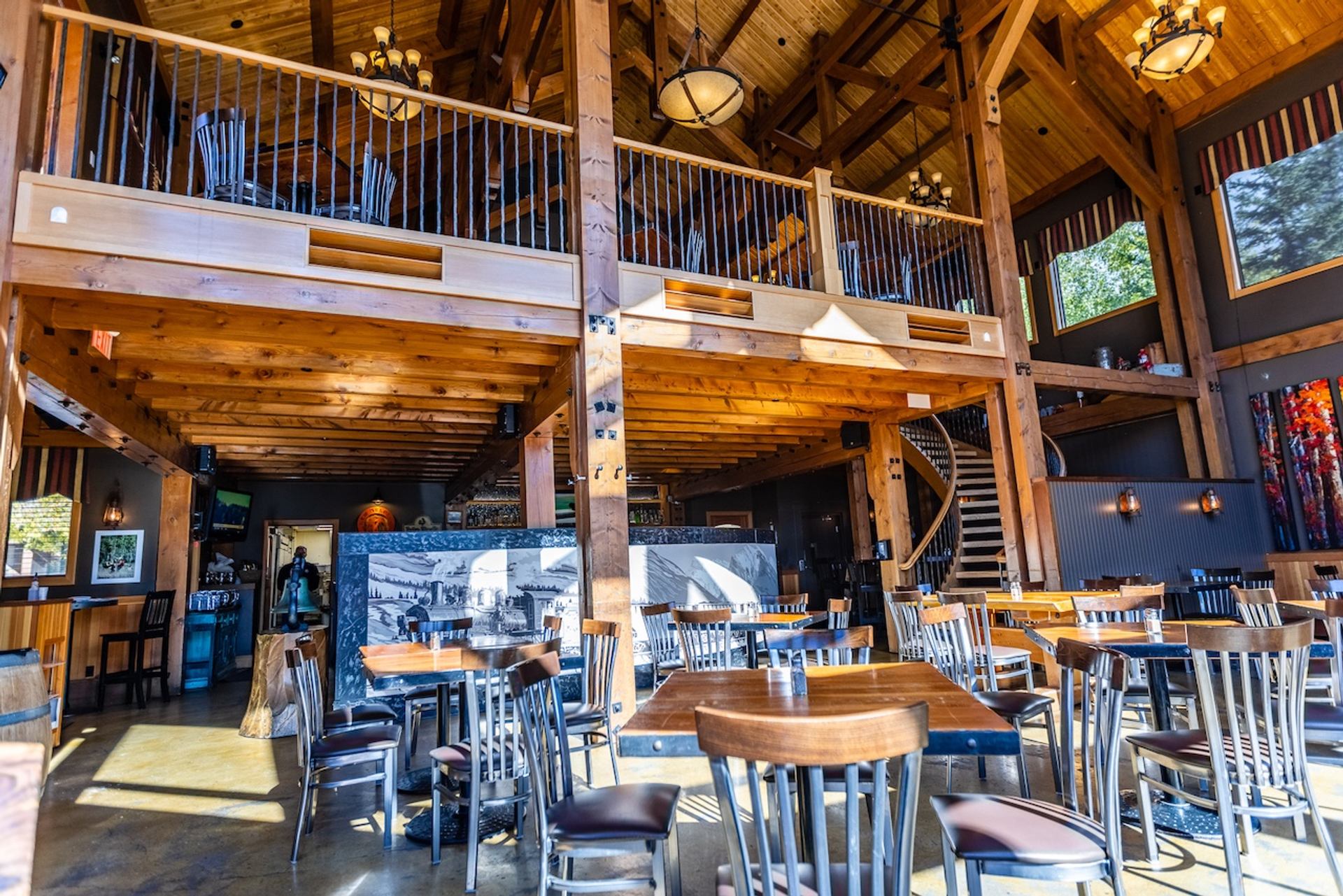 Large dining hall with tall wooden beams, loft seating, and natural light from multiple windows.