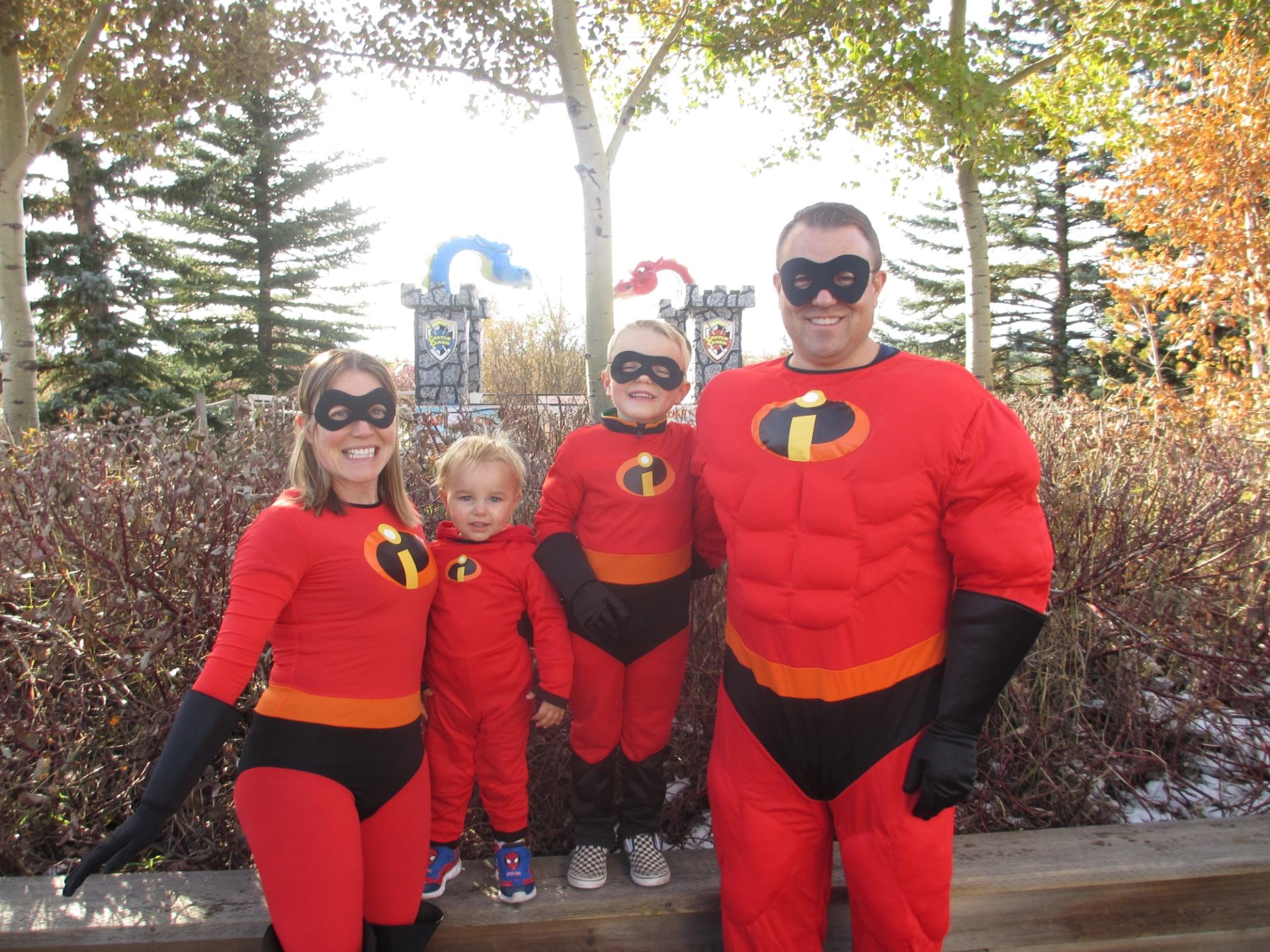 Costumed family posing outdoors at Calaway Park, wearing black face masks and red suits.