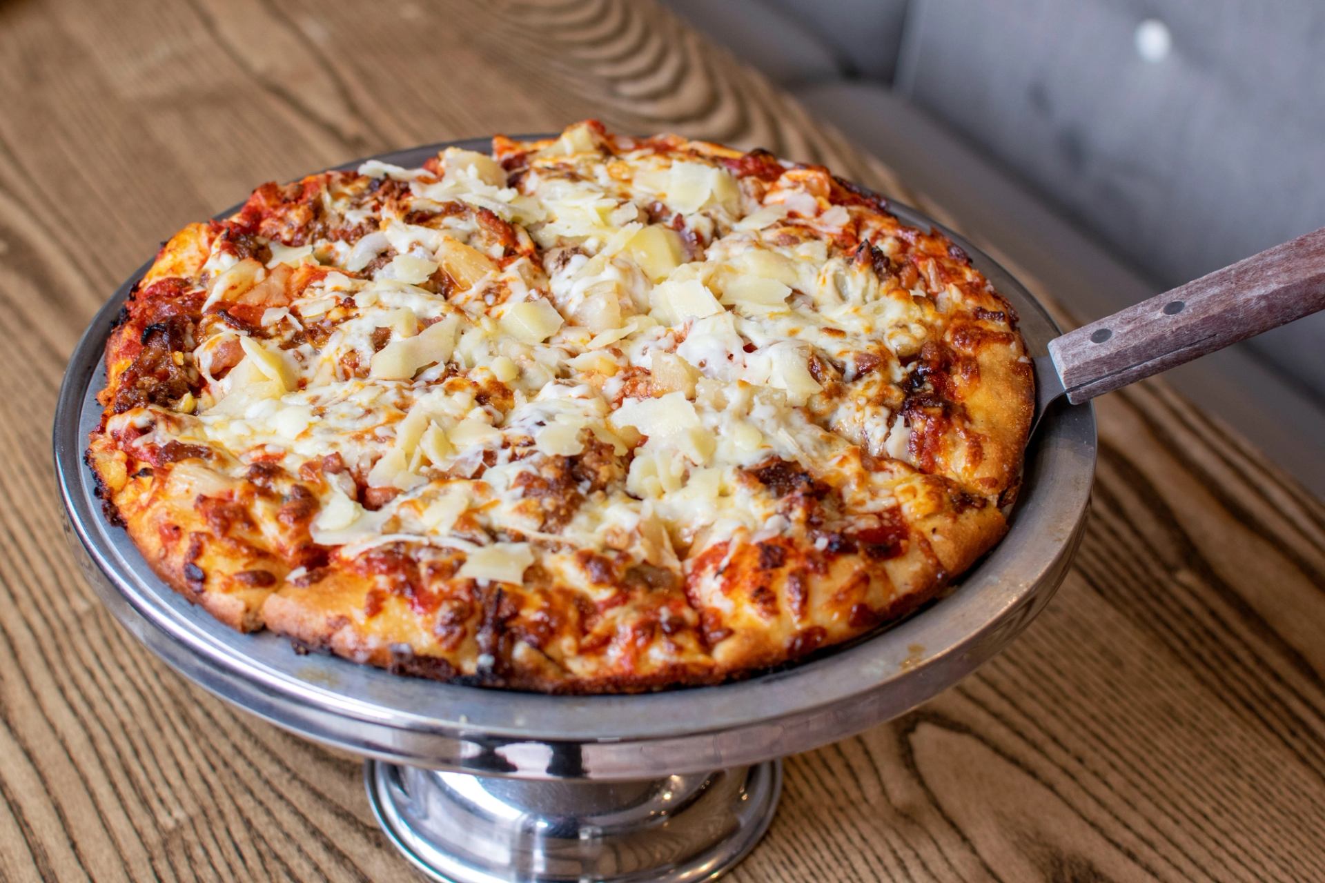 Pretzel bun sandwich with chicken, bacon, cheese, lettuce, and tomato slices.
